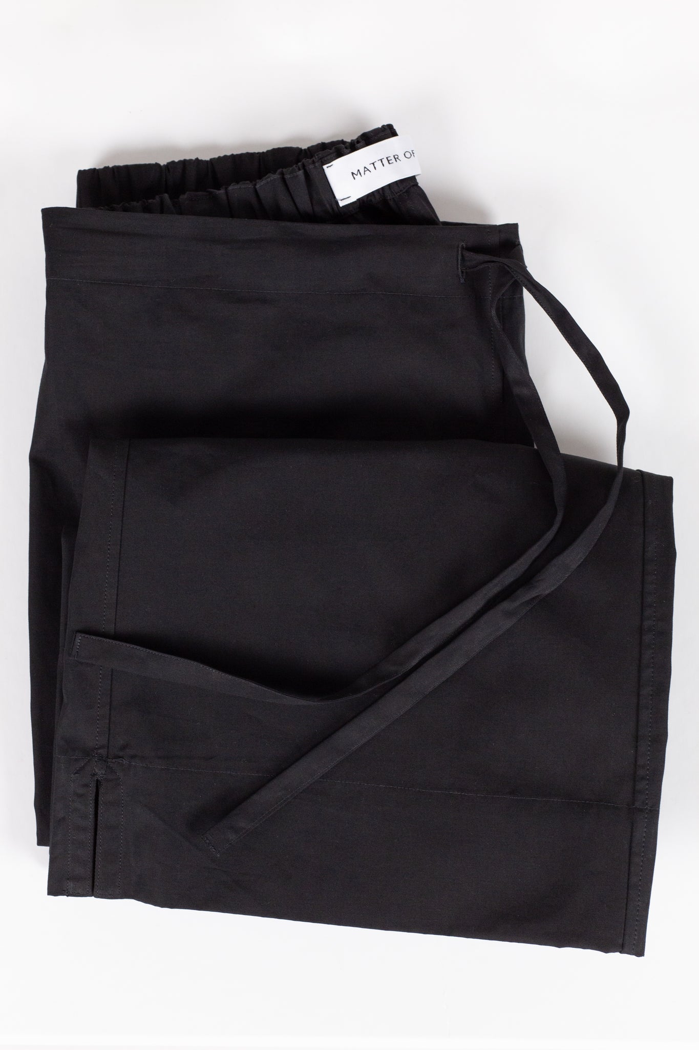Black folded cotton trousers. Drawstring waist.  